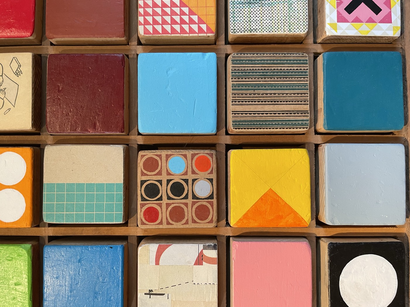 A grid of small hand-painted wood blocks in the studio